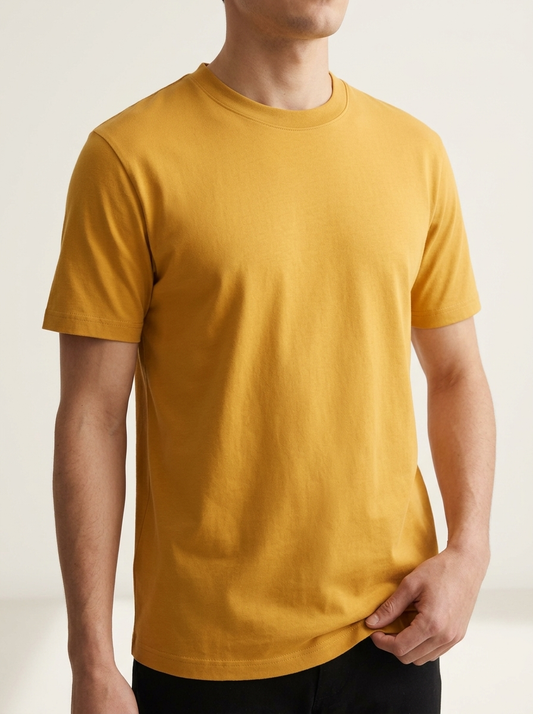 Person wearing a mustard yellow t-shirt against a plain background